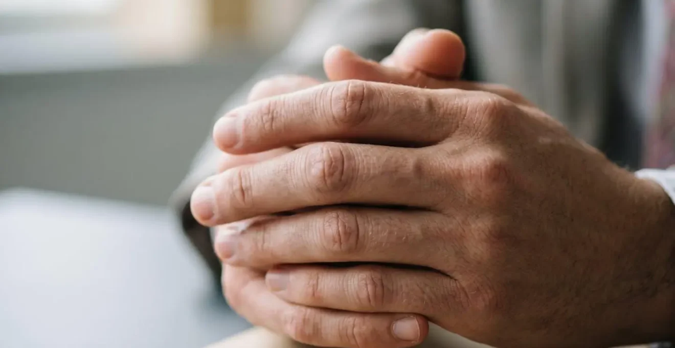 Gros plan sur les mains d'un candidat en posture de réflexion calme lors d'un entretien